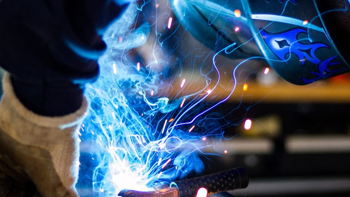 Close-up of a welder at work, with sparks flying from the weld