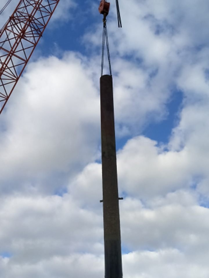 Crane lifting a long steel pile into position