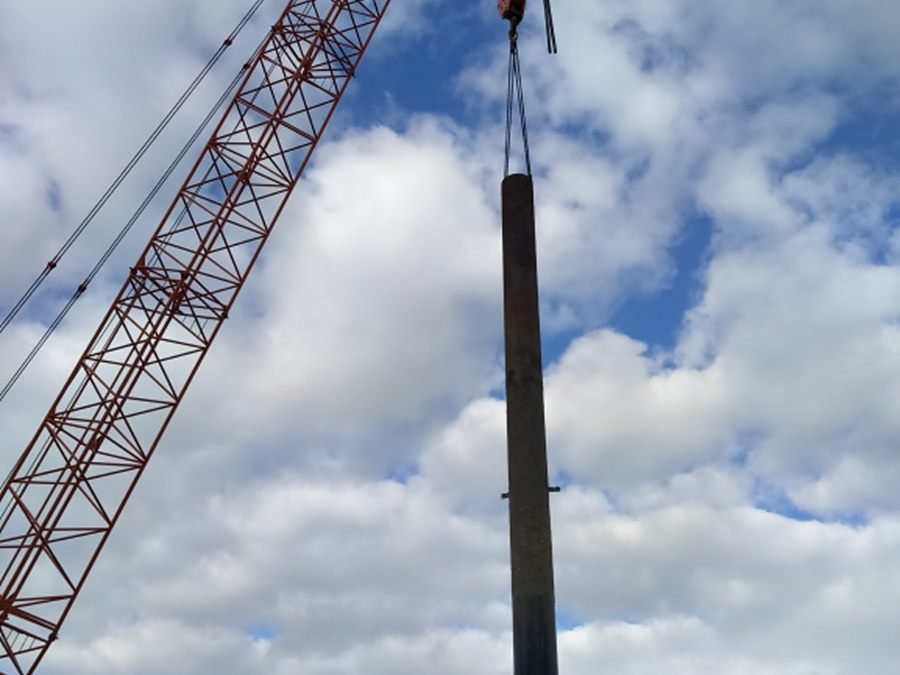 Crane lifting a long steel pile into position