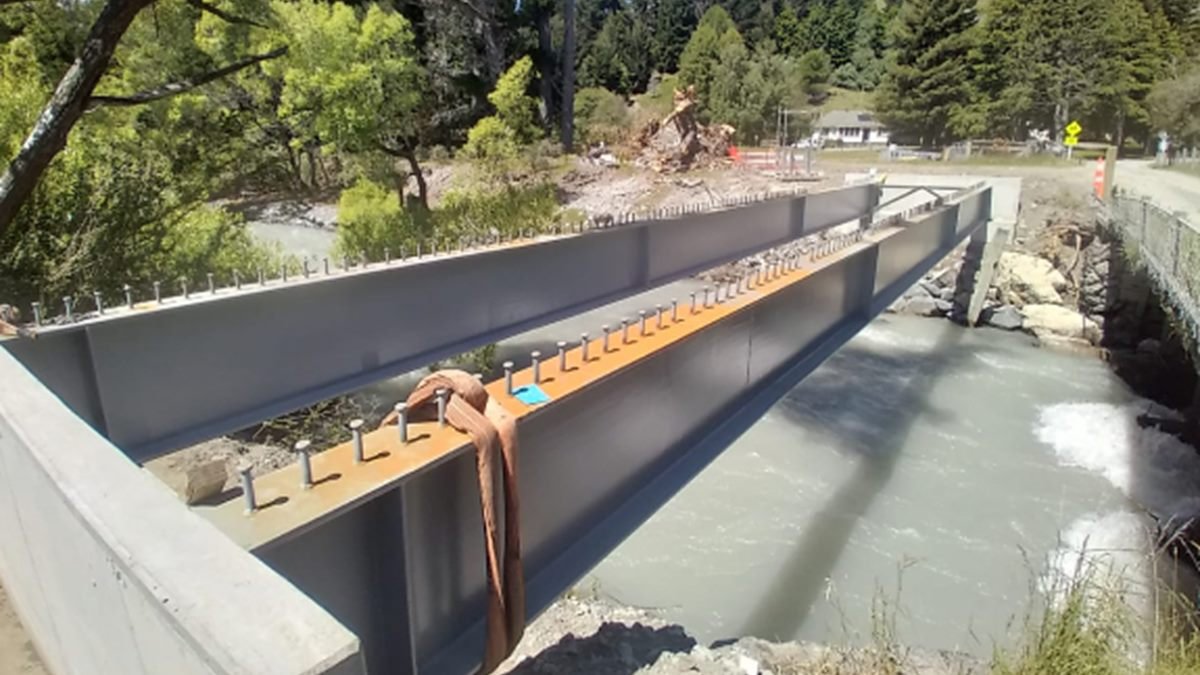 New steel bridge girders spanning a river, with shear studs ready for the deck pour